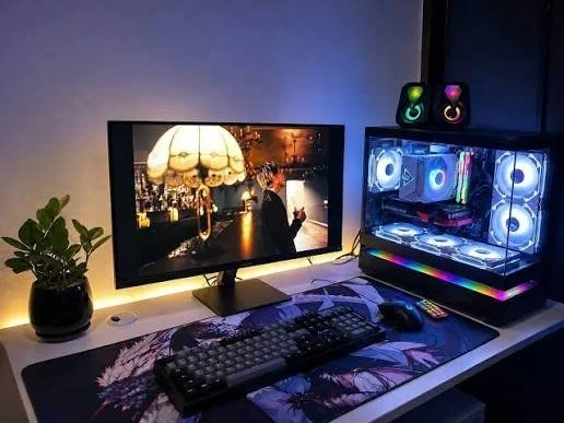 흰 책상 위에 모니터와 RGB 조명이 켜진 PC 본체, 기계식 키보드와 마우스가 놓인 게이밍 PC 환경